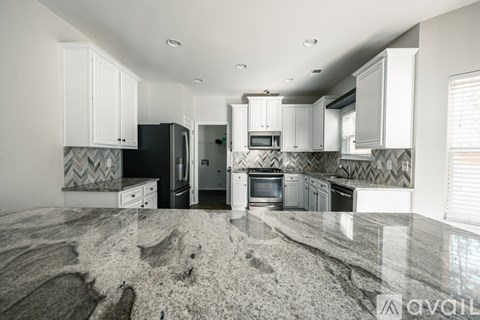 A kitchen with white cabinets and a marble countertop.