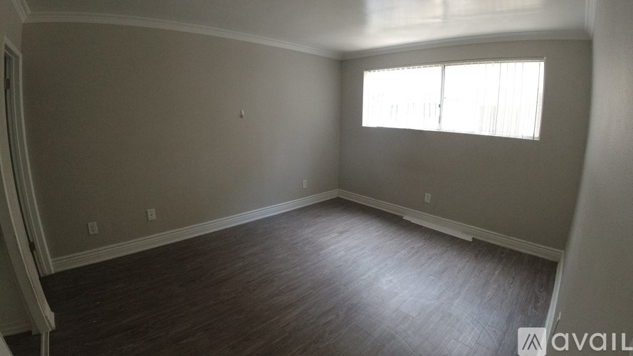 A room with a window and wooden flooring is available for rent.