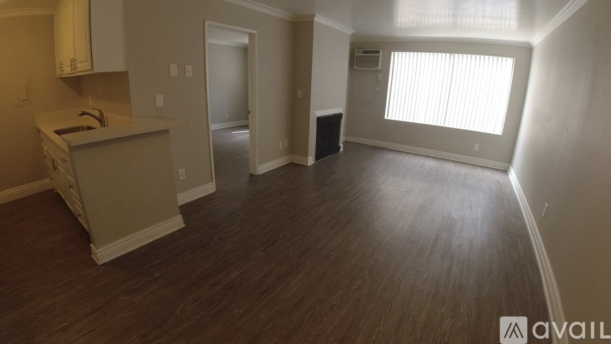 A room with wooden flooring and a window with blinds.