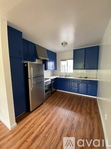 A kitchen with dark blue cabinets and a wooden floor.