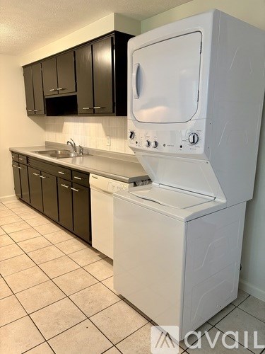 A white dishwasher is in a kitchen with black cabinets.