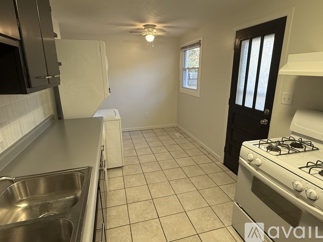 A kitchen with a stove, sink, and cabinets.