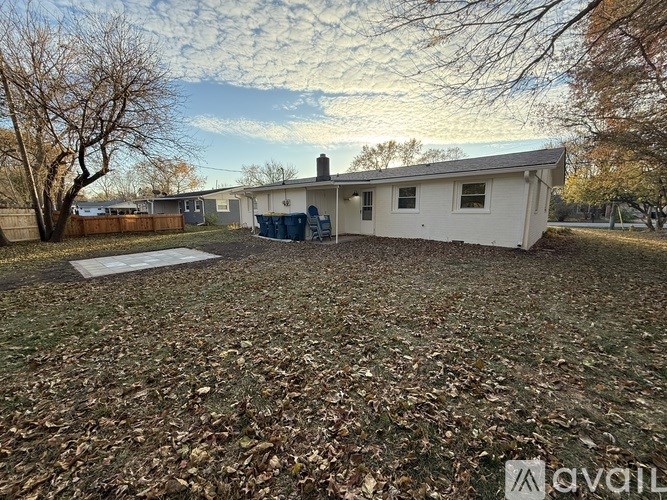 A white house with a brown fence and trees with no leaves.
