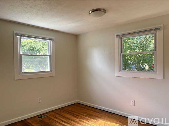 A room with two windows and wooden floors.
