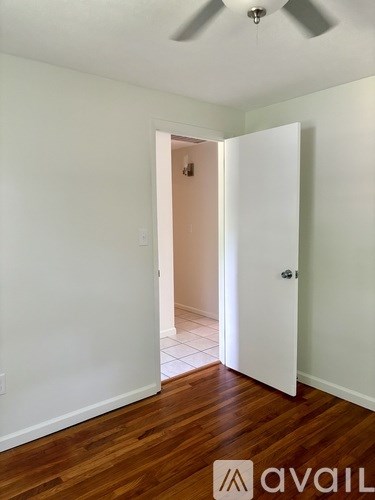 A room with a white door and wooden floor.