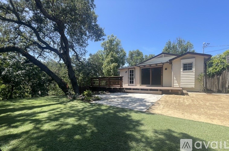 A house with a backyard and a tree in front of it.