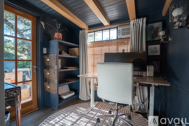 A room with a desk, chair, and a window with blinds.