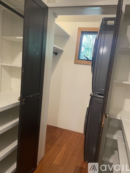 A kitchen with a black fridge and white shelves.