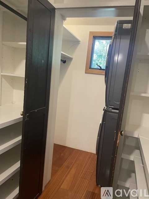 A kitchen with a black fridge and white shelves.
