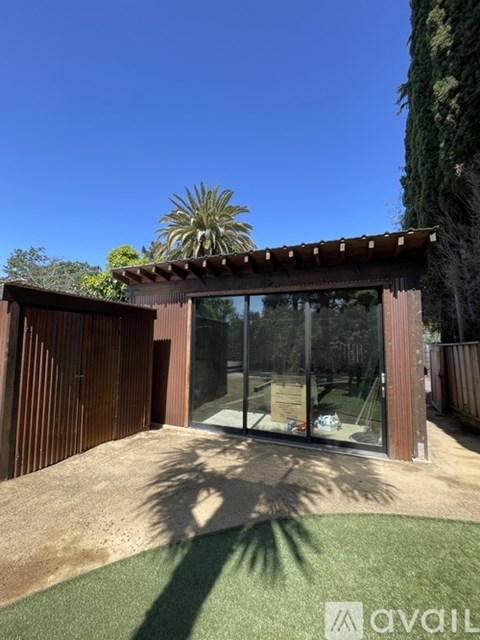 A patio area with a wooden pergola and glass doors.