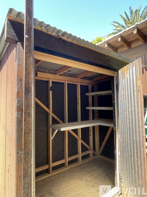 A wooden structure with a roof and a doorway is shown.