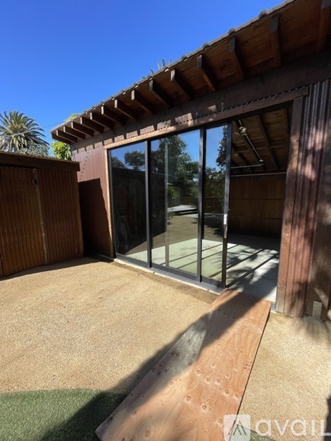 A patio with a wooden roof and glass doors leading to a backyard.
