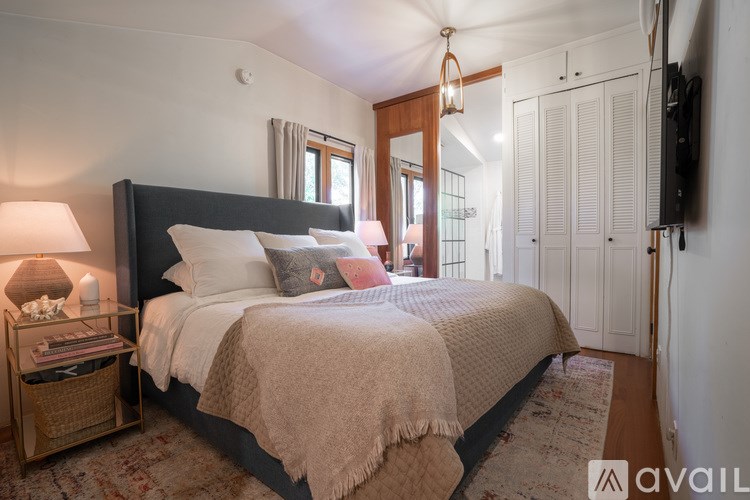A bedroom with a large bed and a TV on the wall.