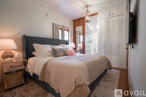 A bedroom with a large bed and a TV on the wall.