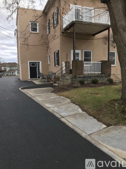 A beige two-story house with a balcony and a black door.