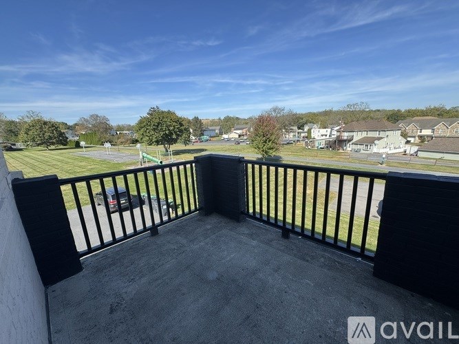 A balcony with a black railing overlooks a residential area.