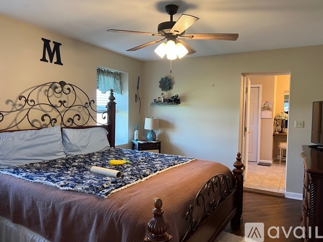 A bedroom with a bed, a ceiling fan, and a nightstand with a lamp.