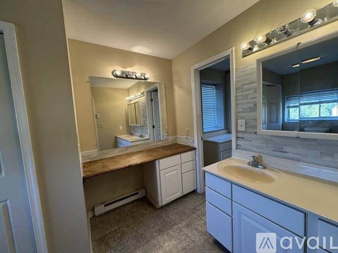 A bathroom with a vanity, sink, mirror, and lighting fixtures.