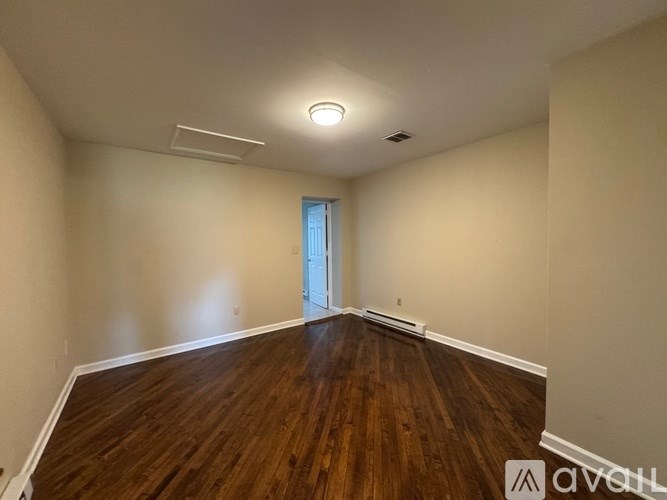 A room with wooden floors and a door in the background.