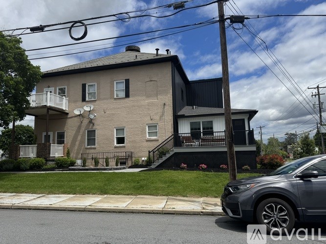 A grey car is parked on the side of a street in front of a house.
