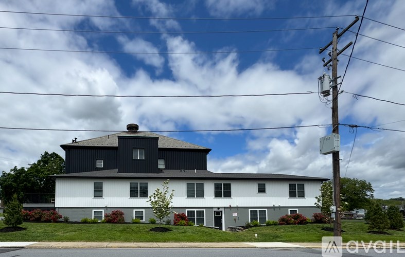 A white house with a black roof and a chimney is shown.