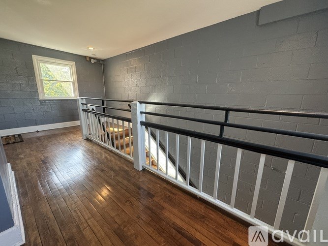A room with wooden floors and a balcony with white railings.