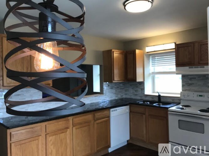 A kitchen with a modern chandelier and wooden cabinets.