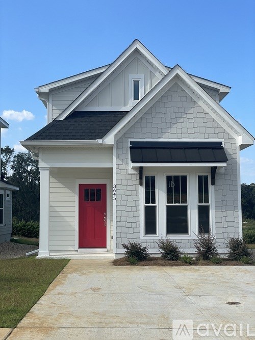 A small white house with a red door and a black awning.
