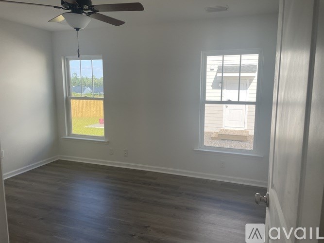 A room with a ceiling fan and two windows.