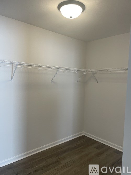 A white wall with a wooden floor and a white ceiling with a light fixture.