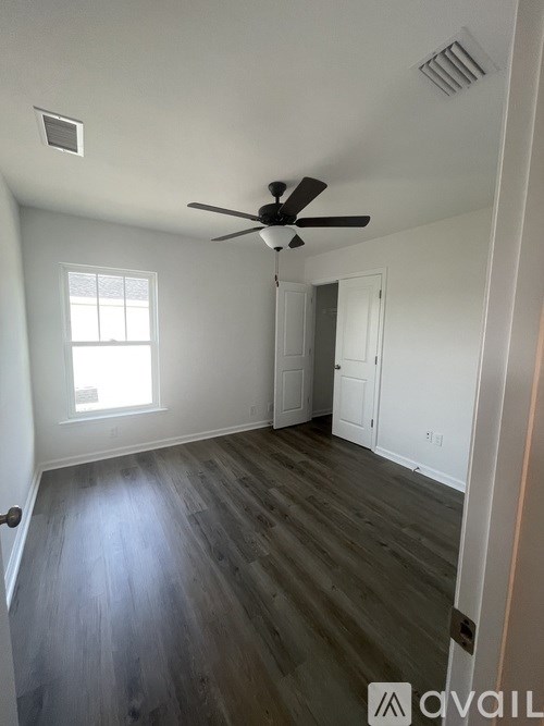 A room with a ceiling fan and wooden flooring.
