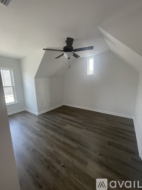A room with a ceiling fan and wooden flooring.