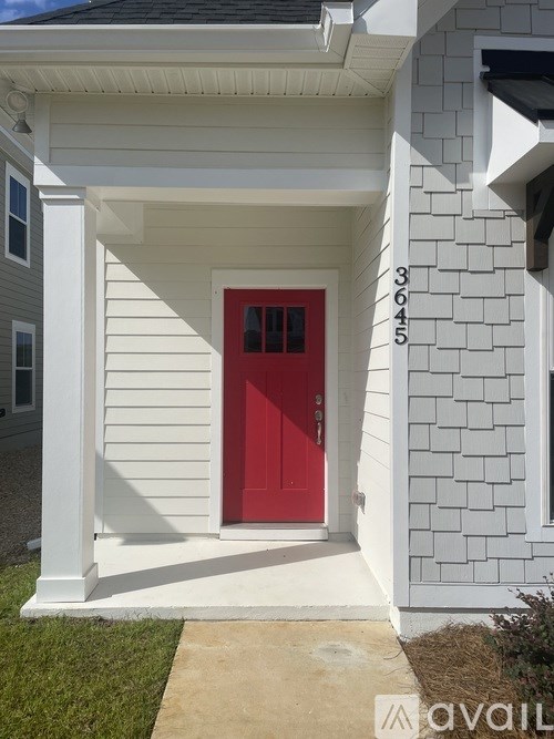 A white house with a red door and the number 3645 on the wall.