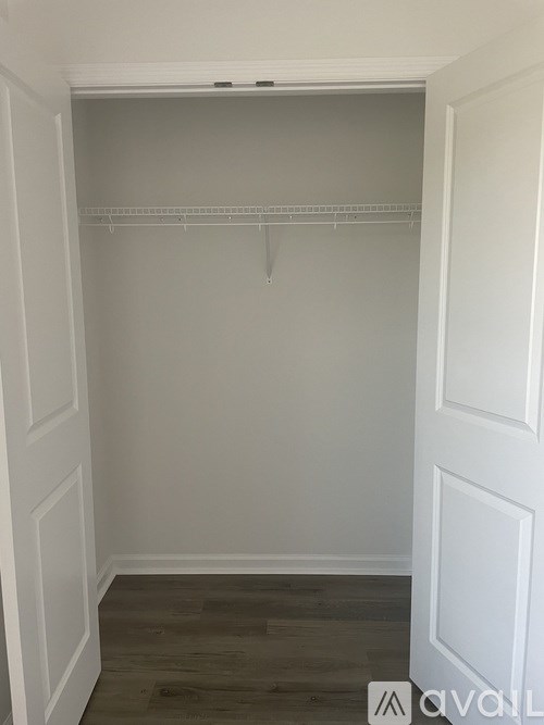 A white closet with a wooden floor and white walls.