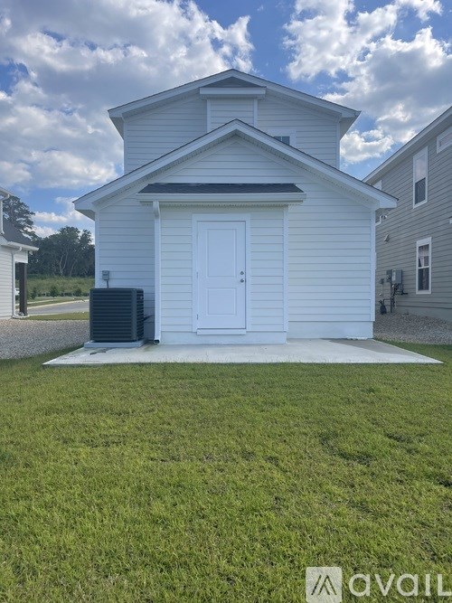 A small white house with a black roof and a white door is for sale.