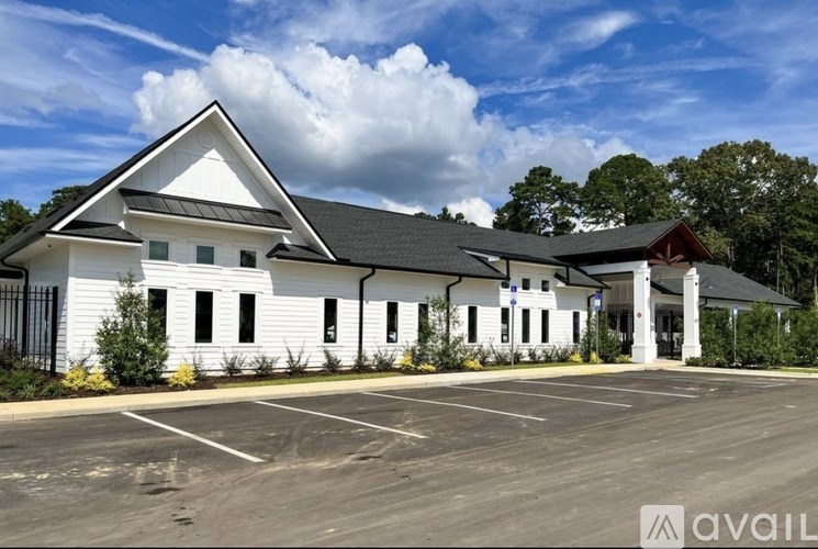 A white building with a black roof and a parking lot in front.