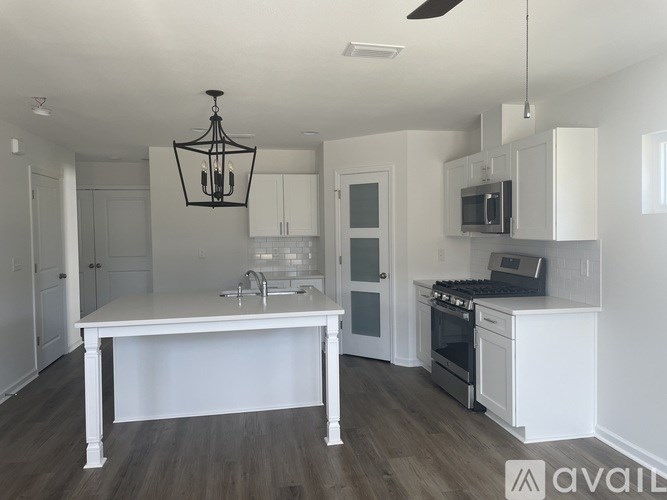 A kitchen with a white island and a black chandelier.