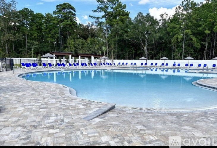 A large outdoor swimming pool surrounded by blue lounge chairs.