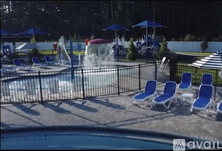 A pool with a waterfall and blue chairs.