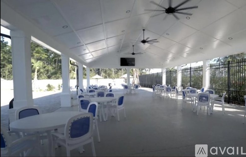 A white patio with tables and chairs and a ceiling fan.