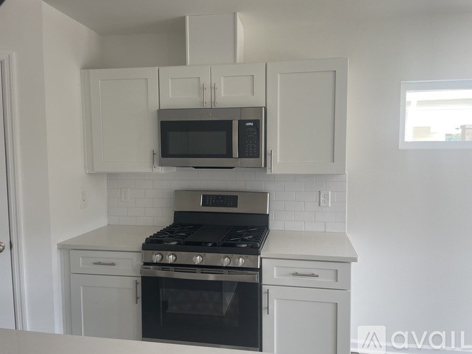 A kitchen with a stove, oven, microwave, and cabinets.