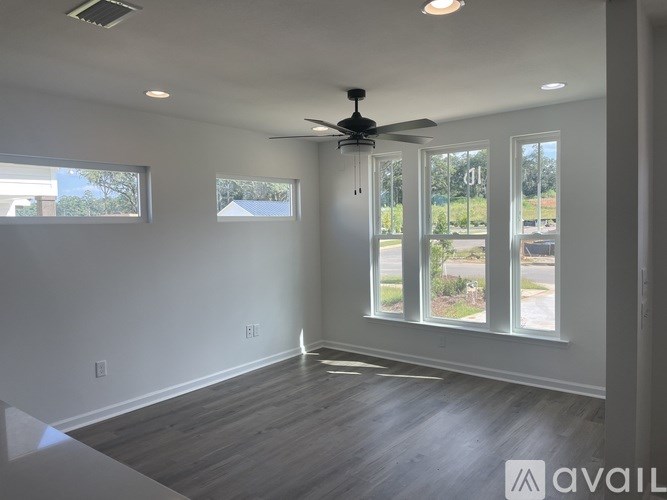 A spacious room with a ceiling fan and large windows.