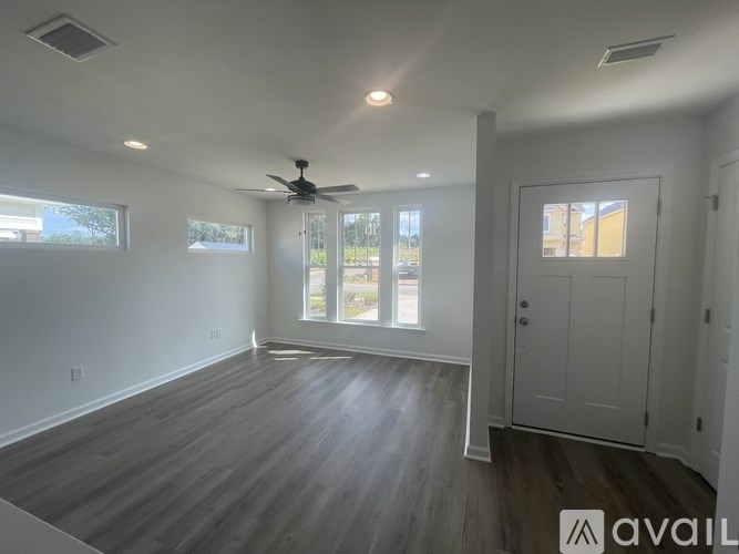 A spacious room with a ceiling fan and hardwood flooring.