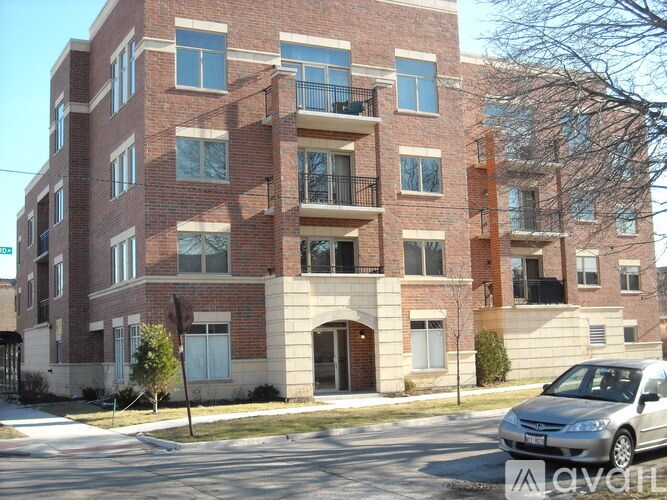 A red brick apartment building with a silver car parked in front.