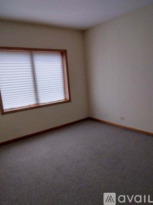 A room with a carpeted floor and a window with blinds.