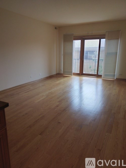 A room with wooden flooring and a balcony with glass doors.