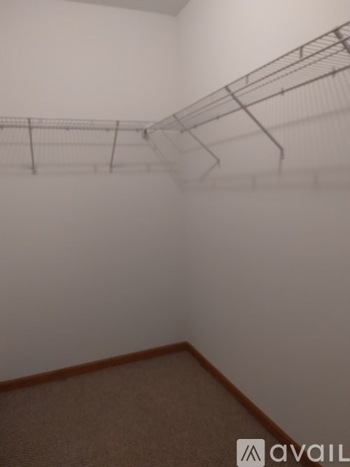 Empty room with a carpeted floor and a metal rack on the wall.