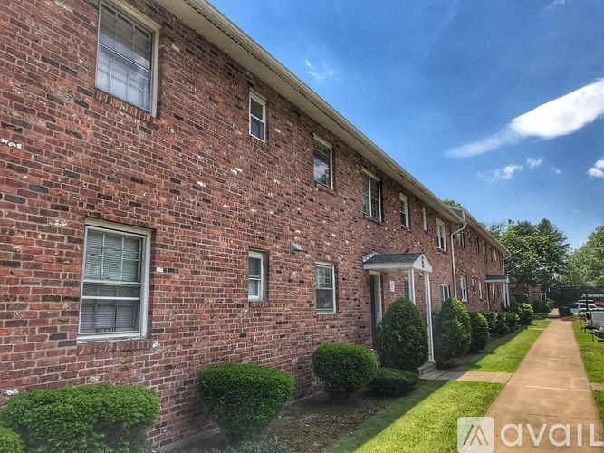 A row of red brick houses with green bushes in front.