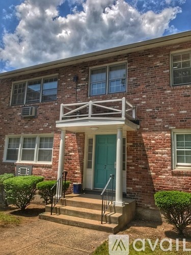 A brick house with a blue door and a white porch.
