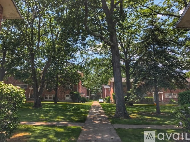 A tree-lined street with a sidewalk and a car parked on the side.